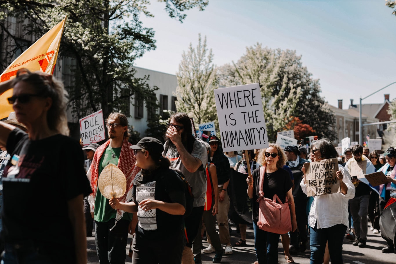 “Community members gather at a rally holding signs, including one reading ‘Where is the humanity?’ showing support for Oregonians affected by SNAP cuts.”